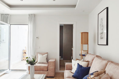 Diseño de salón abierto y beige y blanco actual de tamaño medio sin chimenea con paredes beige, suelo de baldosas de cerámica, televisor colgado en la pared, bandeja y alfombra