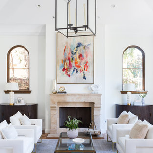 Modelo de salón para visitas abierto, mediterráneo, grande, sin televisor, con paredes blancas, suelo de madera en tonos medios, chimenea tradicional, marco de chimenea de hormigón y suelo marrón