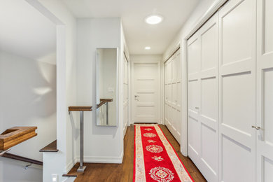Foto de armario unisex contemporáneo de tamaño medio con armarios con paneles empotrados, puertas de armario blancas, suelo de madera en tonos medios y suelo marrón