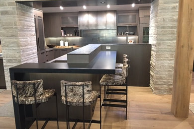 Example of a mid-sized minimalist l-shaped light wood floor and beige floor eat-in kitchen design in Denver with an undermount sink, flat-panel cabinets, gray cabinets, gray backsplash and a peninsula