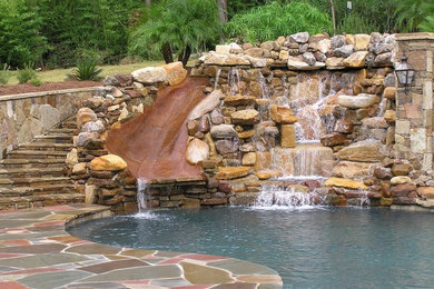 Inspiration for a large rustic backyard stone and custom-shaped lap water slide remodel in New Orleans