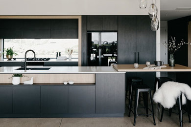 Photo of a large contemporary galley eat-in kitchen in Other with an undermount sink, flat-panel cabinets, grey cabinets, quartz benchtops, white splashback, window splashback, black appliances, concrete floors, with island, grey floor and white benchtop.