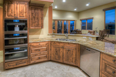 Eat-in kitchen - mid-sized traditional l-shaped ceramic tile eat-in kitchen idea in Phoenix with a drop-in sink, raised-panel cabinets, brown cabinets, granite countertops and stainless steel appliances