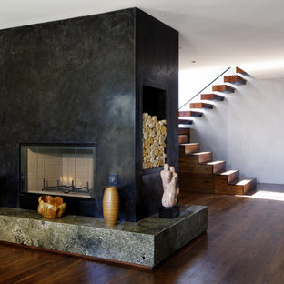 Bild på ett mellanstort funkis separat vardagsrum, med gröna väggar, mellanmörkt trägolv, en dubbelsidig öppen spis och en spiselkrans i sten