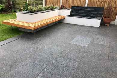 Design ideas for a medium sized contemporary back patio in Hertfordshire with natural stone paving.