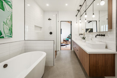 Example of a mid-sized trendy master white tile and ceramic tile concrete floor and gray floor bathroom design in Phoenix with flat-panel cabinets, medium tone wood cabinets, white walls, an undermount sink, solid surface countertops, a hinged shower door and white countertops