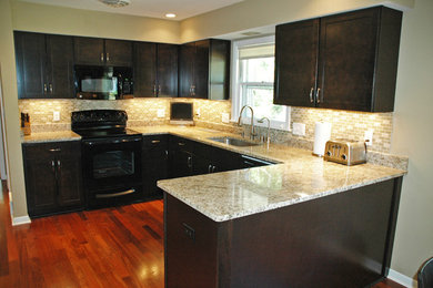 Small trendy u-shaped dark wood floor eat-in kitchen photo in Milwaukee with an undermount sink, recessed-panel cabinets, dark wood cabinets, granite countertops and black appliances