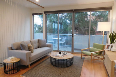 This is an example of a small contemporary open concept living room in Melbourne with white walls and medium hardwood floors.