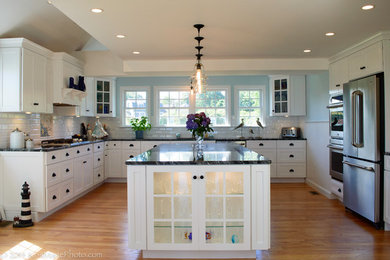 Photo of a large beach style u-shaped eat-in kitchen in Boston with beaded inset cabinets, white cabinets, granite benchtops, white splashback, subway tile splashback, stainless steel appliances, light hardwood floors and with island.