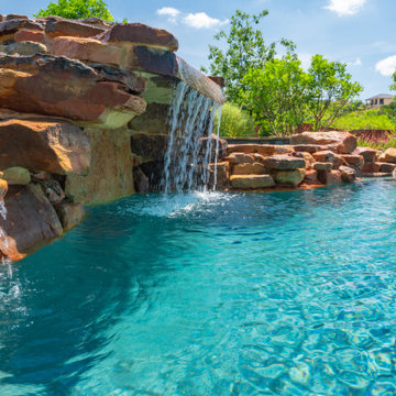 Freeform pool with weeping wall, grotto, and spa in San Antonio, Tx
