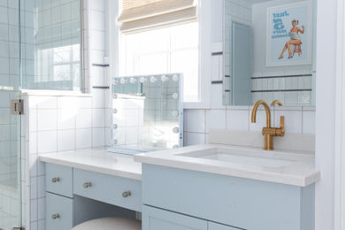 Alcove shower - mid-sized transitional kids' white tile and ceramic tile multicolored floor and single-sink alcove shower idea in Detroit with shaker cabinets, blue cabinets, a two-piece toilet, white walls, quartz countertops, a hinged shower door, white countertops, a niche and a built-in vanity