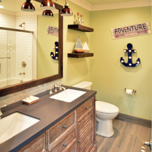 Modelo de cuarto de baño infantil, de estilo de casa de campo, pequeño, con armarios tipo mueble, puertas de armario con efecto envejecido, ducha empotrada, sanitario de dos piezas, baldosas y/o azulejos grises, baldosas y/o azulejos de porcelana, paredes verdes, suelo de baldosas de porcelana, lavabo bajoencimera y encimera de cuarzo compacto