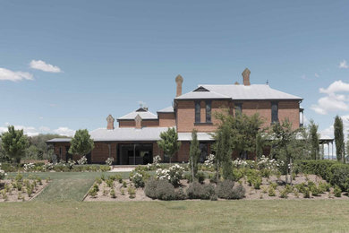 Photo of a victorian two-storey brick house exterior in Other with a metal roof and a grey roof.