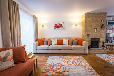 Inspiration for a large contemporary living room in Berkshire with white walls, medium hardwood flooring, a standard fireplace, a brick fireplace surround, a wall mounted tv and brown floors.