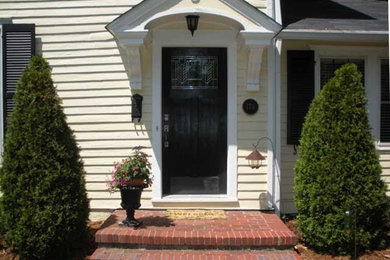Example of a large eclectic brick floor entryway design in Louisville with yellow walls and a black front door