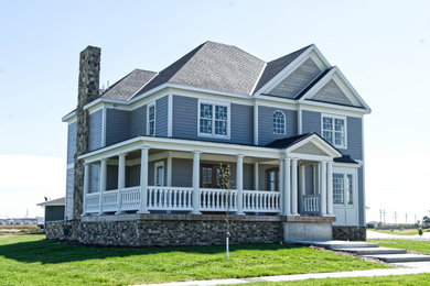 Example of a large cottage gray two-story concrete fiberboard house exterior design in Other with a hip roof and a shingle roof