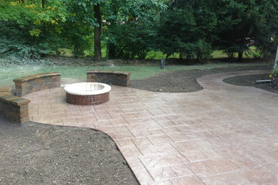 This is an example of a mid-sized traditional backyard patio in Cleveland with a fire feature, concrete pavers and no cover.