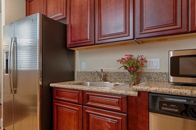 Inspiration for a small timeless ceramic tile and brown floor enclosed kitchen remodel in Houston with a drop-in sink, raised-panel cabinets, dark wood cabinets, granite countertops, beige backsplash, stainless steel appliances and no island