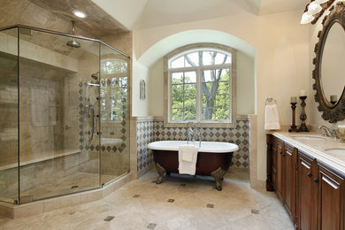 Inspiration for a large traditional master bathroom in Tampa with raised-panel cabinets, dark wood cabinets, a claw-foot tub, a corner shower, beige walls, an undermount sink, granite benchtops, beige tile, brown tile, ceramic tile, ceramic floors, beige floor and a hinged shower door.