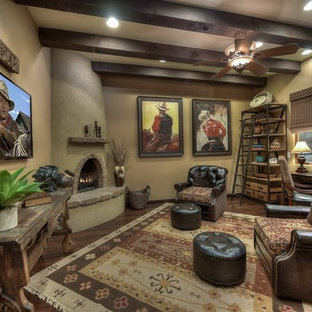 Exempel på ett stort amerikanskt hemmabibliotek, med beige väggar, mörkt trägolv, en öppen hörnspis, en spiselkrans i betong och ett fristående skrivbord