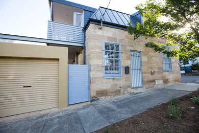 Photo of a mid-sized mediterranean two-storey beige exterior in Sydney with stone veneer.