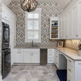 ローリーの大きいトランジショナルスタイルのおしゃれな家事室 (アンダーカウンターシンク、白いキャビネット、クオーツストーンカウンター、マルチカラーの壁、上下配置の洗濯機・乾燥機、グレーのキッチンカウンター、シェーカースタイル扉のキャビネット、グレーの床) の写真