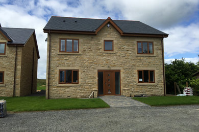 Large and multi-coloured traditional detached house in Other with three floors, stone cladding, a pitched roof and a tiled roof.