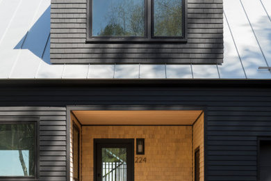 Modelo de fachada de casa negra y gris minimalista de tamaño medio de dos plantas con revestimiento de madera, tejado a dos aguas, tejado de metal y teja