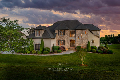 Example of a large classic beige three-story stone house exterior design in Charlotte