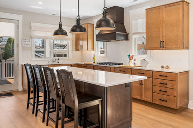 Large classic l-shaped kitchen/diner in Philadelphia with recessed-panel cabinets, engineered stone countertops, white splashback, stainless steel appliances, an island and white worktops.