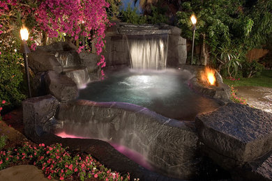 Photo of a small country natural pool in Orange County with natural stone pavers and a hot tub.