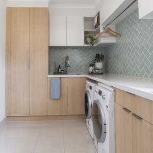 Foto di una lavanderia scandinava con ante in legno chiaro, top in quarzo composito, paraspruzzi verde, paraspruzzi in gres porcellanato, pavimento in gres porcellanato, lavatrice e asciugatrice affiancate, pavimento beige e top bianco