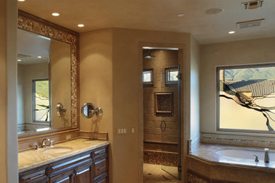 Bathroom - large contemporary master brown tile and stone tile limestone floor and beige floor bathroom idea in Phoenix with raised-panel cabinets, dark wood cabinets, brown walls, an undermount sink, granite countertops and a hinged shower door