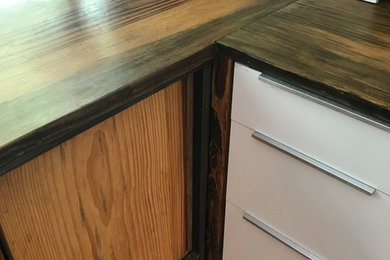 Inspiration for a mid-sized modern l-shaped light wood floor eat-in kitchen remodel in Charleston with an undermount sink, flat-panel cabinets, white cabinets, wood countertops, stainless steel appliances, an island and brown countertops