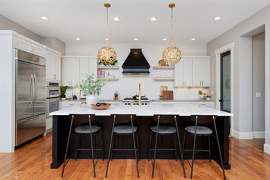 Enclosed kitchen - mid-sized contemporary l-shaped medium tone wood floor enclosed kitchen idea in Denver with an undermount sink, shaker cabinets, white cabinets, marble countertops, white backsplash, stainless steel appliances and an island