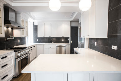 This is an example of a large contemporary eat-in kitchen in New York with an undermount sink, shaker cabinets, white cabinets, quartz benchtops, black splashback, porcelain splashback, stainless steel appliances, medium hardwood floors and a peninsula.