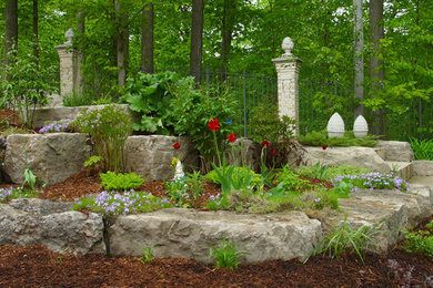Photo of a mid-sized traditional partial sun hillside mulch retaining wall landscape in Toronto.