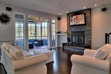 Example of a large trendy open concept dark wood floor living room design in Montreal with gray walls, a standard fireplace, a stone fireplace and a wall-mounted tv