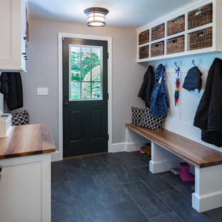 Foto på ett eklektiskt kapprum, med grå väggar, skiffergolv, en enkeldörr, en svart dörr och grått golv