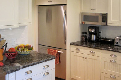 Example of a small cottage u-shaped light wood floor enclosed kitchen design in San Luis Obispo with an undermount sink, shaker cabinets, white cabinets, granite countertops, white backsplash, ceramic backsplash, white appliances and a peninsula