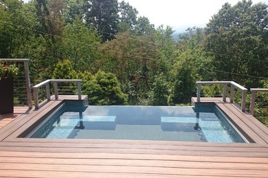 This is an example of a mid-sized contemporary rooftop rectangular infinity pool in Other with tile.
