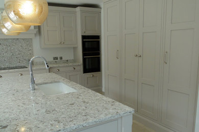 Photo of a large classic kitchen/diner in London with a double-bowl sink, shaker cabinets, an island and quartz worktops.
