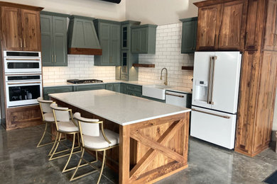 Example of a concrete floor and gray floor eat-in kitchen design in Other with a farmhouse sink, shaker cabinets, green cabinets, solid surface countertops, white backsplash, subway tile backsplash, white appliances, an island and white countertops