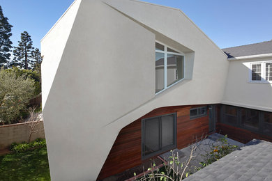 Example of a small trendy beige two-story stucco house exterior design in Los Angeles with a clipped gable roof and a shingle roof
