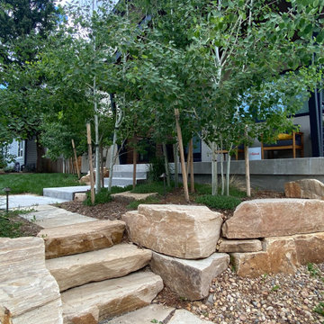 Mountain inspired minimalist boulder retaining walls and plantings.