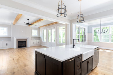 Large transitional single-wall light wood floor and brown floor eat-in kitchen photo in Other with a farmhouse sink, shaker cabinets, brown cabinets, quartz countertops, white backsplash, porcelain backsplash, stainless steel appliances, an island and white countertops