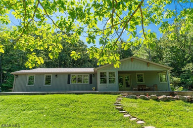 Mid-sized arts and crafts green one-story vinyl exterior home photo in Other with a shingle roof