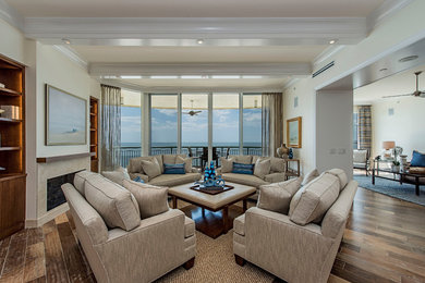 Example of a large beach style formal and open concept medium tone wood floor living room design in Miami with beige walls, a standard fireplace and no tv