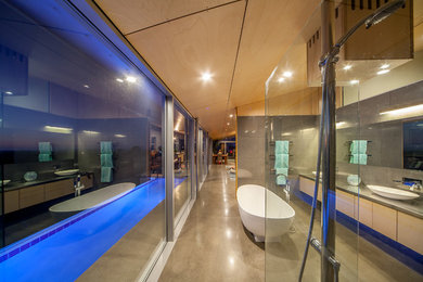 Example of a trendy bathroom design in Auckland with stainless steel countertops, light wood cabinets and flat-panel cabinets