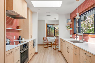 Eat-in kitchen - mid-sized mid-century modern galley light wood floor and beige floor eat-in kitchen idea in Portland with an undermount sink, flat-panel cabinets, light wood cabinets, granite countertops, pink backsplash, ceramic backsplash, paneled appliances, no island and white countertops